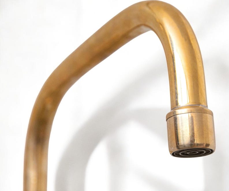 May include: A gold-toned faucet with a curved spout and a round, aerated nozzle.