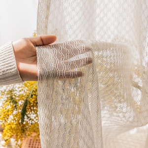 Puede incluir: Panel de cortina blanca y transparente con un patrón ondulado texturizado. La cortina está hecha de una tela ligera y tiene una sensación delicada y aireada.