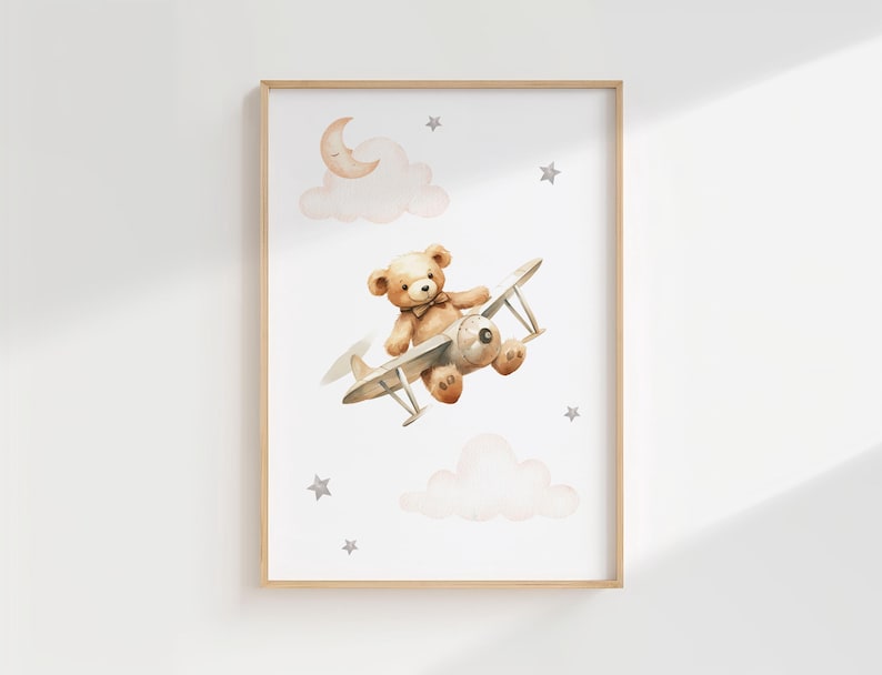 Pode incluir: Ilustra&ccedil;&atilde;o em aquarela de um urso de pel&uacute;cia pilotando um avi&atilde;o vintage, em um fundo branco com nuvens, estrelas e uma lua crescente. A obra de arte &eacute; emoldurada em uma moldura de madeira clara, ideal para decora&ccedil;&atilde;o de ber&ccedil;&aacute;rio.