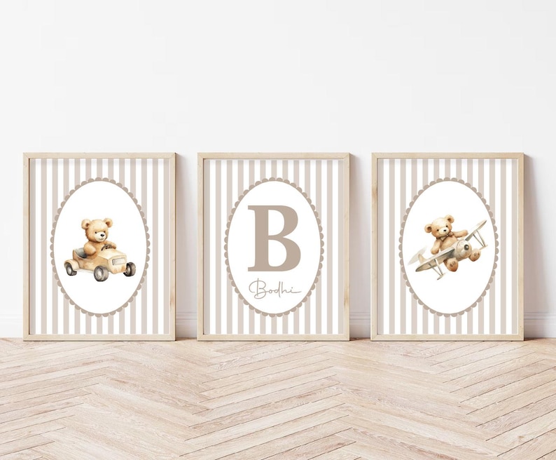 May include: Three framed nursery art prints. Each print features a watercolour illustration of a teddy bear. One bear is in a car, one is in an aeroplane, and the third has the letter "B" and the name "Bodhe". The background has a striped pattern.