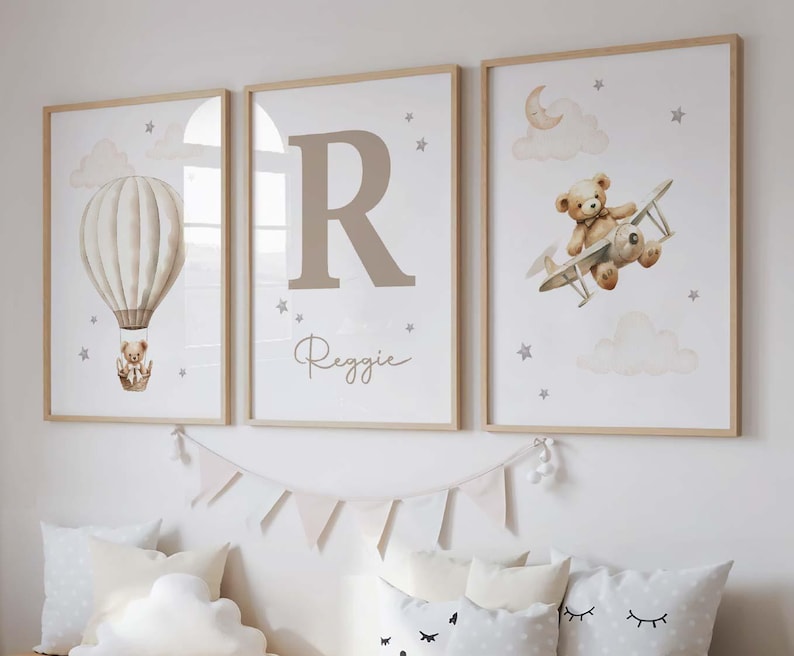 Pode incluir: Tr&ecirc;s impress&otilde;es de arte emolduradas para o ber&ccedil;&aacute;rio. Uma apresenta um bal&atilde;o de ar quente com um ursinho de pel&uacute;cia, outra exibe a letra "R" com o nome "Reggie", e a terceira mostra um ursinho de pel&uacute;cia em um biplano. Tudo em tons neutros.