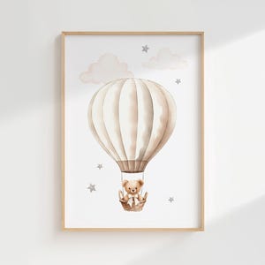 Pode incluir: Ilustra&ccedil;&atilde;o em aquarela de um bal&atilde;o de ar quente com um ursinho de pel&uacute;cia em uma cesta, em um fundo branco com nuvens e estrelas. A obra de arte &eacute; emoldurada em uma moldura de madeira clara, ideal para um quarto infantil.
