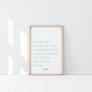 Op de afbeelding: Een ingelijste print met een licht houten frame. De print bevat de quote "WHEN THE POWER OF LOVE OVERCOMES THE LOVE OF POWER, THE WORLD WILL KNOW PEACE." in turquoise tekst. De quote wordt toegeschreven aan Jimi Hendrix.