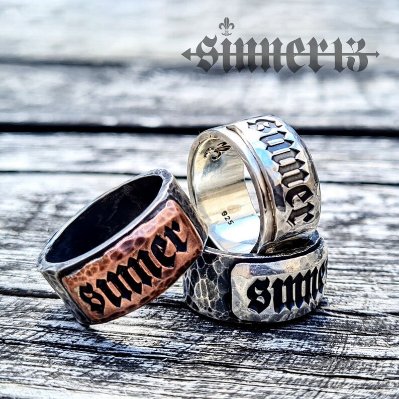 May include: Three silver rings with the word "Summer" engraved on each. The rings are stacked on top of each other. The top ring is smooth, the middle ring has a hammered texture, and the bottom ring has a textured surface.