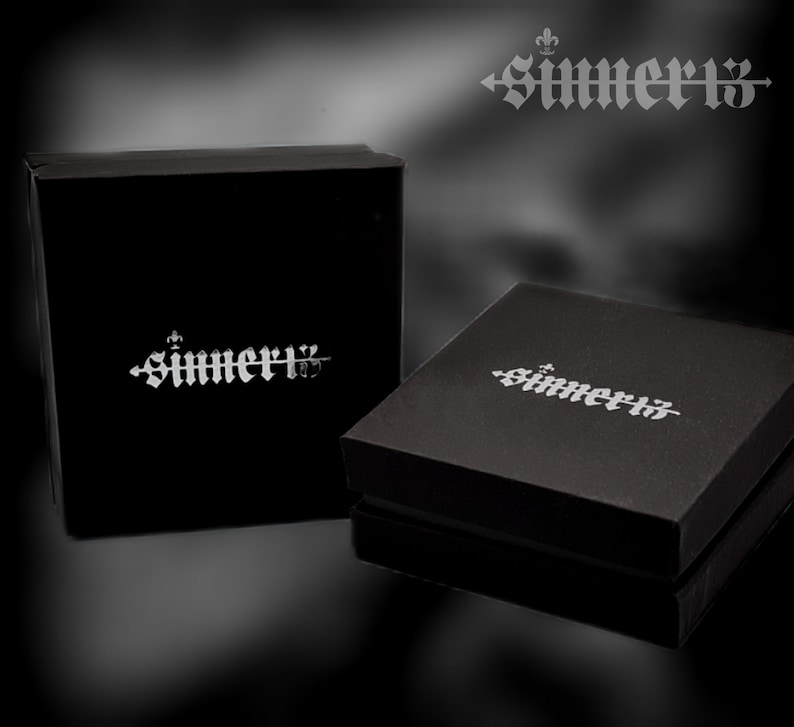 May include: Two black boxes with the word "SIMMER13" printed in silver on the top. The boxes are on a black background.