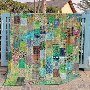 Pode incluir: Uma colcha de retalhos retangular com uma variedade de quadrados de tecido verdes, azuis e multicoloridos com diversos padrões florais, geométricos e abstratos. A colcha exibe detalhes de costura visíveis e o texto Ganeshexport.