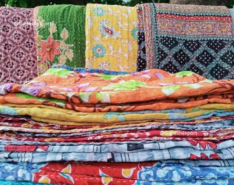 May include: A stack of colorful kantha quilts with floral and paisley patterns. The quilts are made of recycled saris and are hand-stitched.  @Ganeshexport