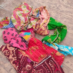May include: A collection of colorful kantha quilts with intricate patterns and stitching. The quilts are made from recycled saris and are a popular choice for home decor and gifts.