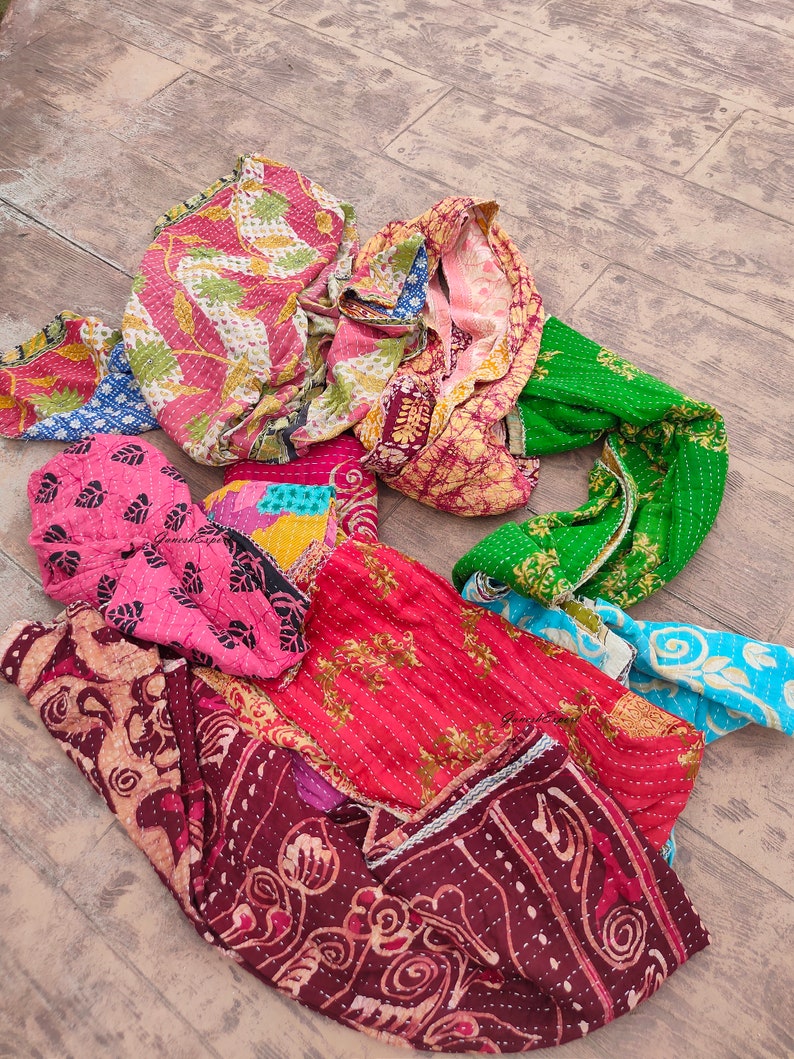 May include: A collection of colorful kantha quilts with intricate patterns and stitching. The quilts are made from recycled saris and are a popular choice for home decor and gifts.