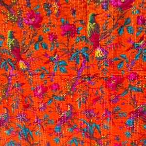 Op de afbeelding: Oranje kantha-deken met een bloemen- en vogelpatroon. De deken heeft een herhalend patroon van roze bloemen, groene bladeren en kleurrijke vogels.