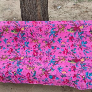 May include: Pink kantha quilt with a floral and bird pattern. The quilt is hand-stitched and features a variety of colors, including pink, blue, green, and yellow.