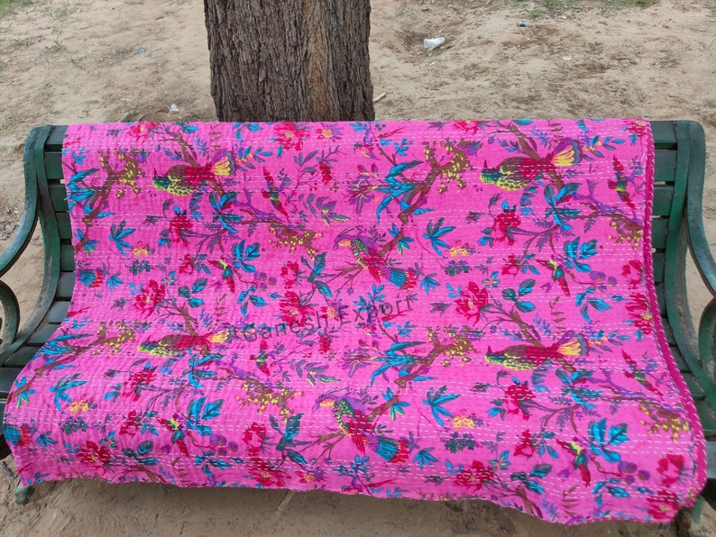 May include: Pink kantha quilt with a floral and bird pattern. The quilt is hand-stitched and features a variety of colors, including pink, blue, green, and yellow.