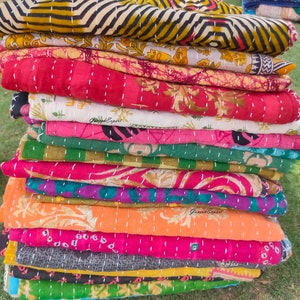 May include: A stack of colourful kantha quilts with intricate patterns and stitching. The quilts are made from recycled saris and are a traditional Indian craft.