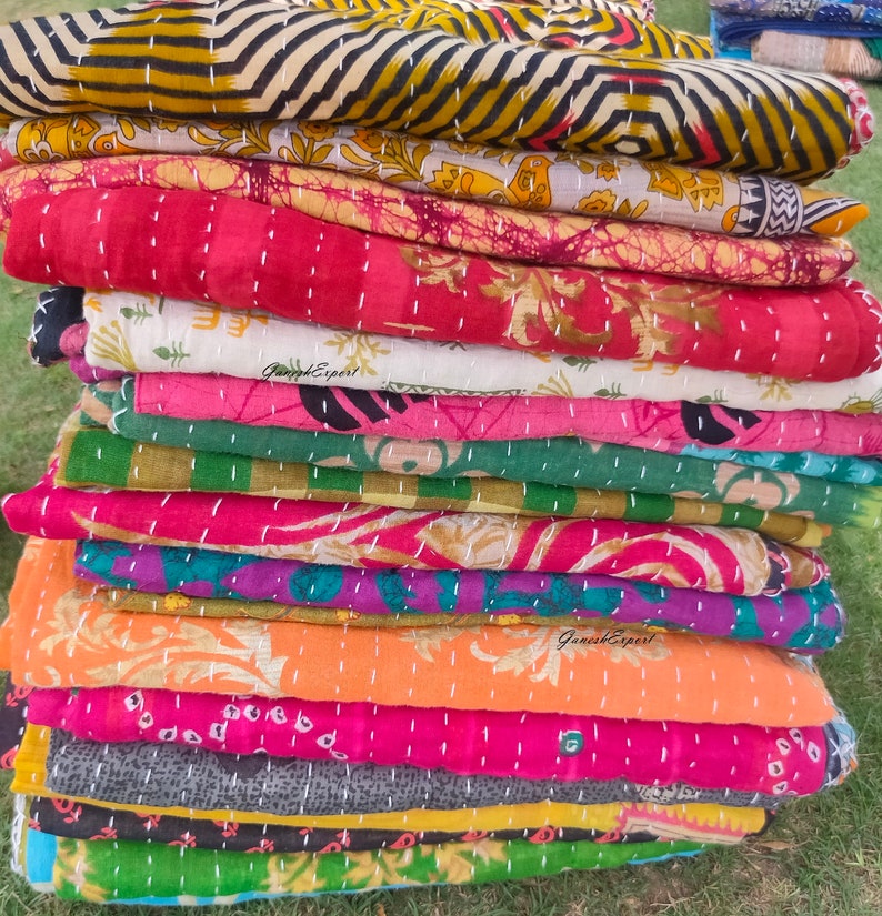 May include: A stack of colourful kantha quilts with intricate patterns and stitching. The quilts are made from recycled saris and are a traditional Indian craft.
