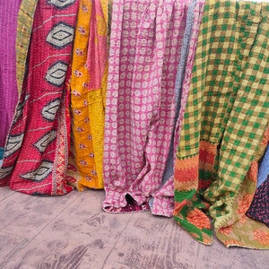 May include: A collection of colourful kantha quilts with various patterns, including floral, geometric and plaid designs. The quilts are made from recycled saris and are hand-stitched.