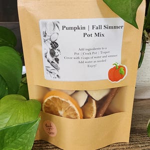 Könnte beinhalten: Ein Kraftpapierbeutel mit einem transparenten Fenster, der getrocknete Orangenscheiben, Zimtstangen und andere Potpourri-Zutaten enthält. Auf dem Etikett steht "Pumpkin | Fall Simmer Pot Mix". Ein kleiner Aufkleber sagt "Danke".