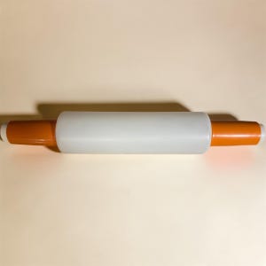 May include: A rolling pin with a white center and orange handles. The rolling pin is designed for baking and features a smooth, cylindrical shape for even dough distribution. The handles are a vibrant orange color.