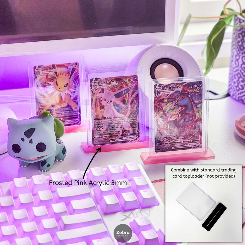 May include: Three pink acrylic card display stands with Pokemon trading cards. The stands are 3mm thick and are designed to hold standard trading cards. The text "Frosted Pink Acrylic 3mm" is visible on the image.