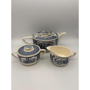 Pode incluir: Um conjunto de chá vintage azul e branco com uma chaleira, um jarro de creme e um açucareiro. O conjunto apresenta um padrão floral azul e branco.