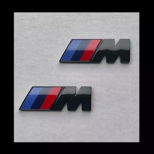 x2 BMW M emblem, 55 x 20 mm NEW black glossy lettering, self-adhesive, sticker, new in foil, trunk