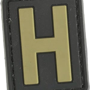 May include: A black and tan fabric patch with the letter "H" in a large, bold font.