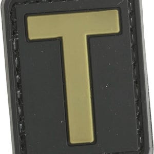 May include: Black patch with a gold letter T in the center. The patch has a stitched border.