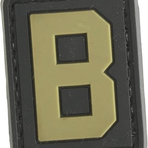 May include: A black and tan velcro patch with the letter "B" in a large, bold font.