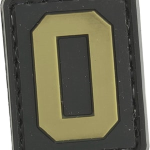May include: A black and tan velcro patch with the number "0" in a large, bold font.
