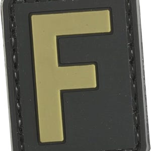 May include: A black and gold letter F patch with a stitched border. The patch is made of a durable material and is perfect for adding a personal touch to your gear.