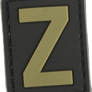 May include: A black patch with a gold letter Z in the center. The patch has a stitched border.