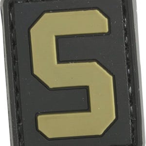 Puede incluir: Parche de velcro negro y marrón con el número "5" en una fuente en negrita y de bloque.