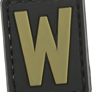 May include: A black and tan fabric patch with the letter "W" in a large, bold font.