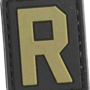 May include: A black and tan fabric patch with the letter "R" in a bold, blocky font.