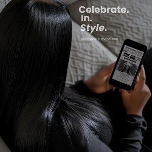 May include: A person holding a black smartphone with a graduation announcement on the screen. The announcement reads "She Did It!" and features a photo of a woman in a graduation cap and gown. The text "Celebrate. In. Style." is visible above the phone.