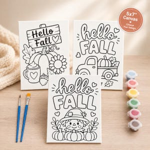May include: Three 5x7 inch white canvases with black line art for painting. Designs include a pumpkin with a mug, a truck with a pumpkin, and a scarecrow with pumpkins. Includes two paintbrushes and a strip of six small paint pots with various colors.