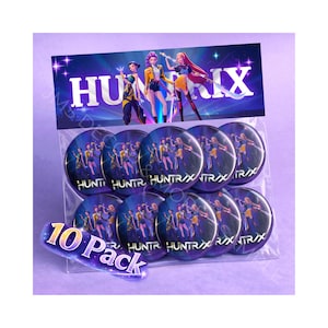 May include: A clear plastic bag containing a 10-pack of round buttons. Each button features a group of animated characters in colorful outfits. The bag's header displays the word "HUNTRIX" in white letters against a purple background.