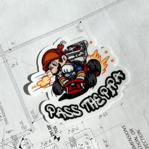 May include: A white sticker with a cartoon character driving a red go-kart. The character is wearing a red hat and overalls. The sticker has the text "PASS THE PIPA" in black letters.