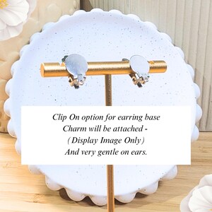 K&ouml;nnte beinhalten: Ein Paar silberne Clip-Ohrring-Basen auf einem goldenen St&auml;nder. Der Text lautet: "Clip On option for earring base Charm will be attached - (Display Image Only) And very gentle on ears."