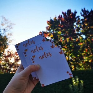 May include: Three white notepads with a fall leaf design border. Each notepad has the word "notes" written in orange cursive.