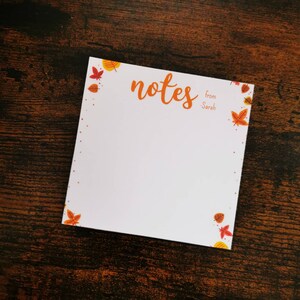 May include: A white notepad with a fall leaf border. The notepad has the word "notes" written in cursive and the words "from Sarah" written below.
