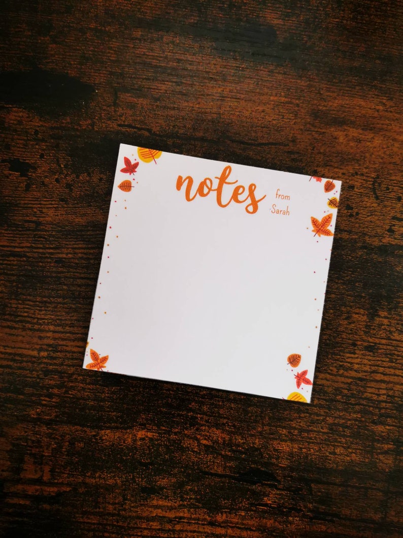 May include: A white notepad with a fall leaf border. The notepad has the word "notes" written in cursive and the words "from Sarah" written below.
