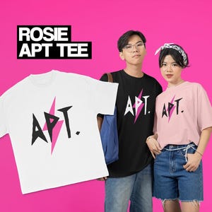 May include: Two people wearing black and pink t-shirts with the text "APT." and a pink lightning bolt graphic. The shirts are available in black, white, and pink.