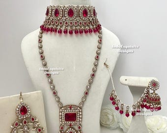 May include: A complete jewelry set featuring a choker, long necklace, earrings, and headpiece. The pieces are adorned with red gemstones and clear crystals, set in a silver-toned metal. The set is displayed on a white mannequin.