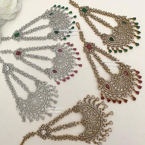 May include: An assortment of ornate headpieces, featuring intricate silver and gold-toned designs. Each piece is adorned with sparkling clear and colored gemstones, including green and red accents. The headpieces have multiple chains and a hook for securing to the hair.