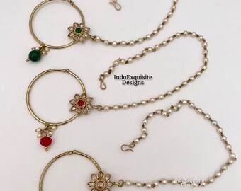 May include: Three gold nose rings with pearl chains. The nose rings have a flower design with different colored stones. The first nose ring has a green stone, the second has a red stone, and the third has a white pearl.