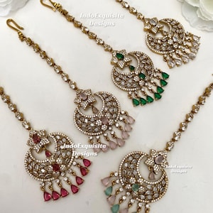 May include: Four gold-toned maang tikka headpieces featuring crescent-shaped pendants adorned with clear crystals and teardrop-shaped stones in green, pink, red, and light blue. Each piece includes a delicate chain with a hook attachment.