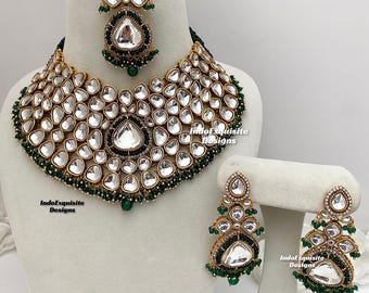 May include: A gold and green Indian bridal necklace set with a large teardrop pendant and matching earrings. The necklace is made of gold metal and features a large number of clear stones. The earrings are also made of gold metal and feature a large teardrop pendant with clear stones.