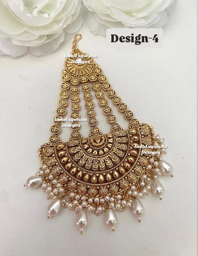 May include: Gold-toned headpiece with intricate embossed detailing and dangling faux pearls. The design features a half-moon shape with multiple strands of circular accents. The text "Design-4" is visible.