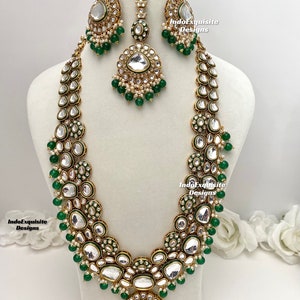 Puede incluir: Un collar de oro con cuentas verdes y blancas y un gran colgante. El collar está sobre un fondo blanco. IndoExquisite Designs.