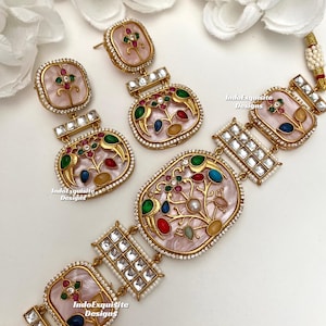 May include: A gold-toned jewelry set featuring a necklace and earrings. The set has pink, oval-shaped pendants with colorful floral designs and clear stone accents. The earrings are studs and drop earrings. The necklace has a matching pendant and square accents.